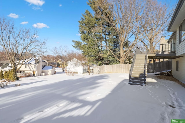 snowy yard featuring a residential view, fence, and stairs