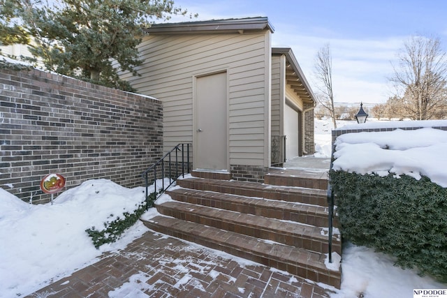 snow covered property entrance with a garage