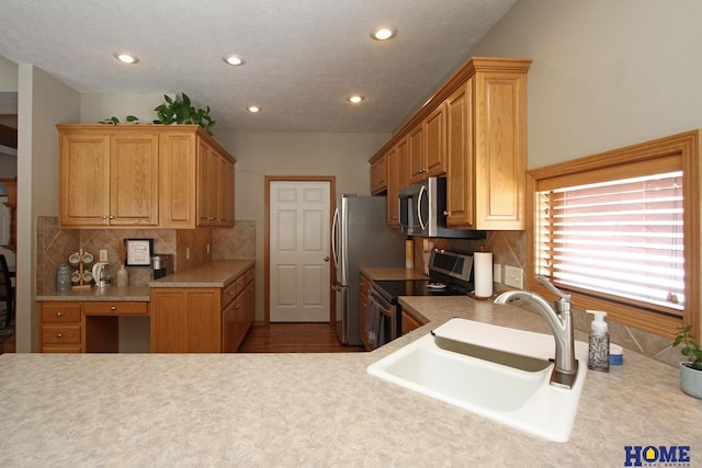 kitchen featuring stainless steel appliances, backsplash, a sink, and light countertops