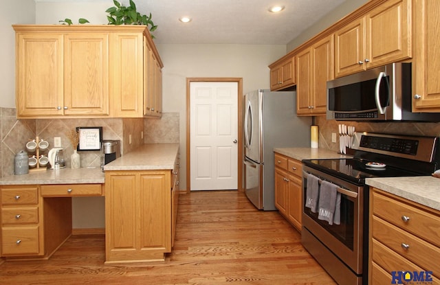 kitchen with stainless steel appliances, light countertops, light wood-style flooring, and built in study area