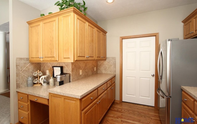 kitchen with wood finished floors, light countertops, decorative backsplash, and freestanding refrigerator