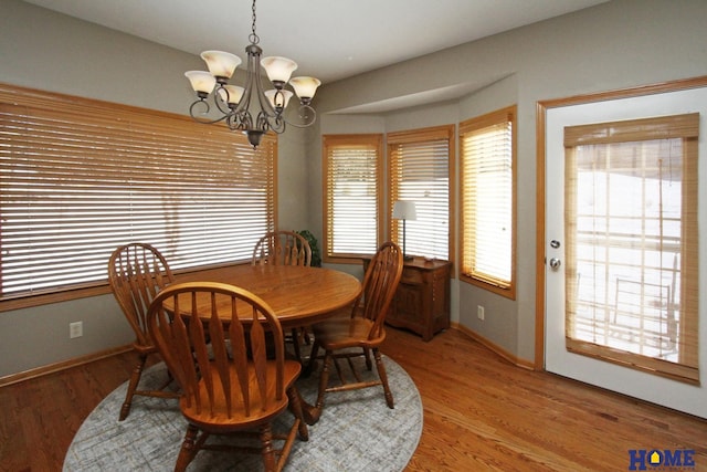 dining area featuring baseboards, light wood finished floors, and an inviting chandelier