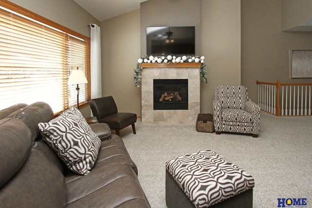 carpeted living room featuring a tile fireplace and lofted ceiling