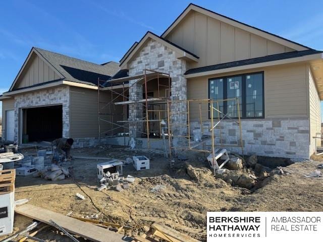 property in mid-construction with stone siding, board and batten siding, and an attached garage