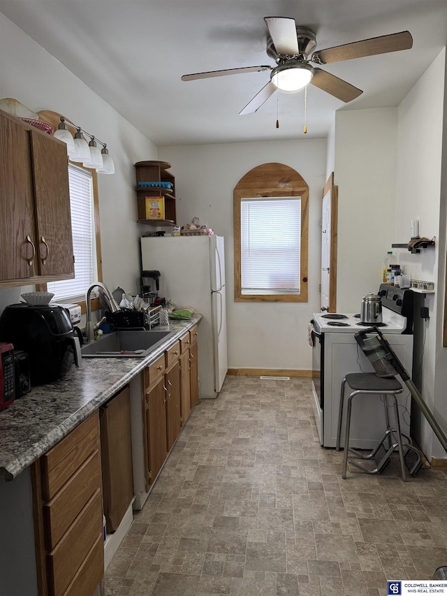 kitchen featuring white appliances, baseboards, a ceiling fan, stone finish floor, and a sink