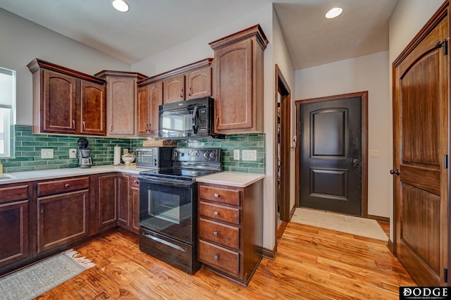 kitchen with black appliances, backsplash, light countertops, and light wood finished floors