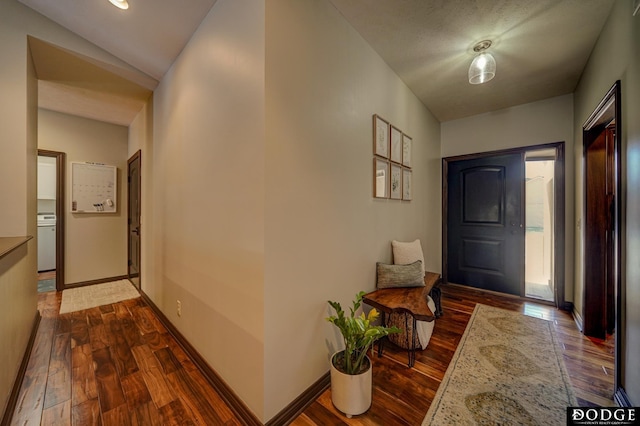 foyer with dark wood finished floors, washer / dryer, and baseboards