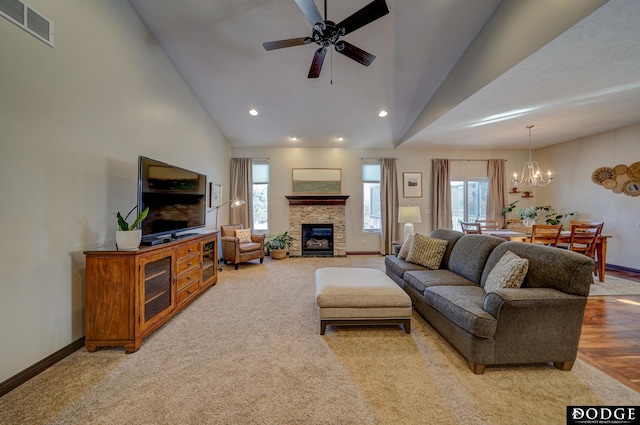 living area featuring high vaulted ceiling, ceiling fan with notable chandelier, a fireplace, visible vents, and baseboards