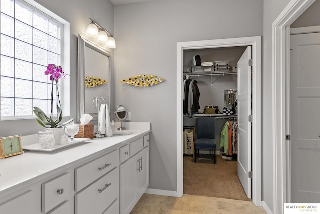 full bath featuring tile patterned floors, a walk in closet, vanity, and baseboards