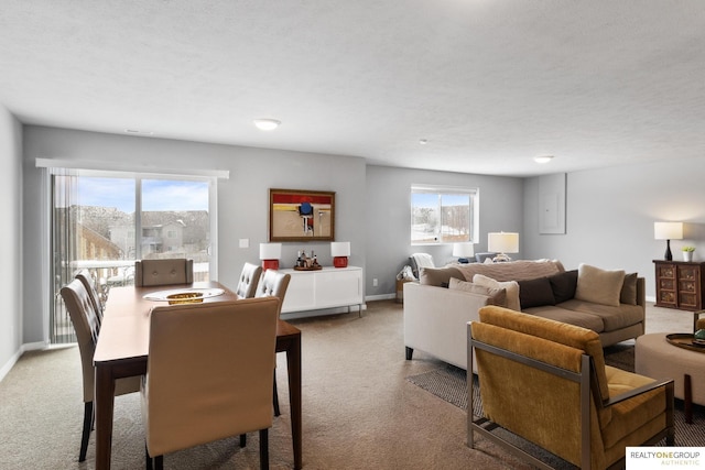 dining space with a textured ceiling, light colored carpet, and baseboards