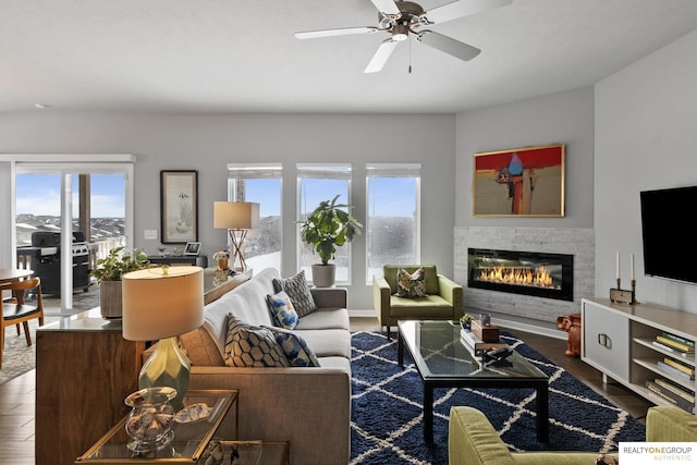 living room with a ceiling fan, a glass covered fireplace, a healthy amount of sunlight, and wood finished floors