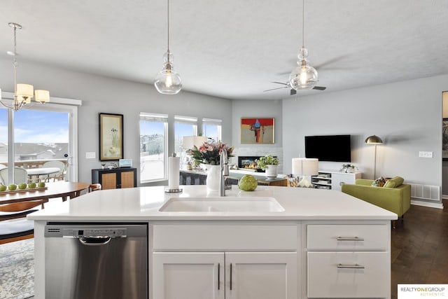 kitchen with light countertops, open floor plan, white cabinetry, a sink, and dishwasher