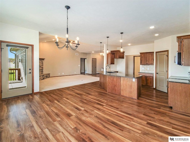 kitchen featuring brown cabinetry, pendant lighting, a chandelier, and open floor plan