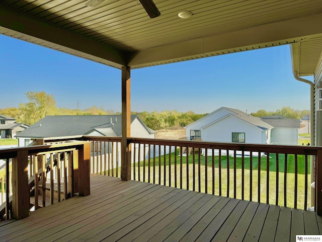 deck with ceiling fan, a residential view, and a lawn