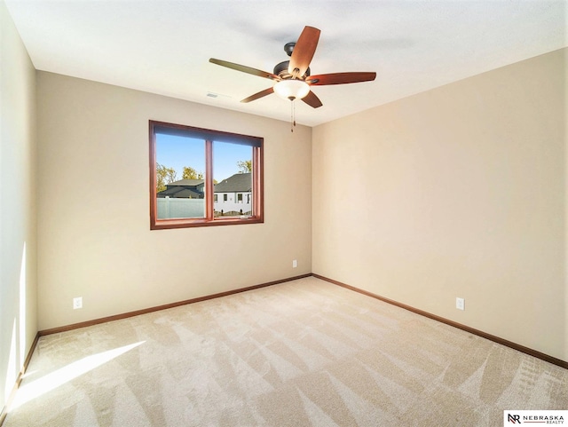 empty room with light colored carpet, ceiling fan, visible vents, and baseboards