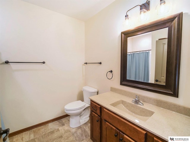 bathroom with toilet, baseboards, and vanity