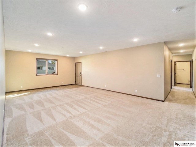 spare room featuring baseboards, recessed lighting, and light colored carpet