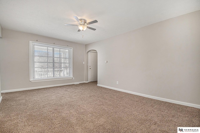 carpeted spare room featuring arched walkways, ceiling fan, a textured ceiling, and baseboards