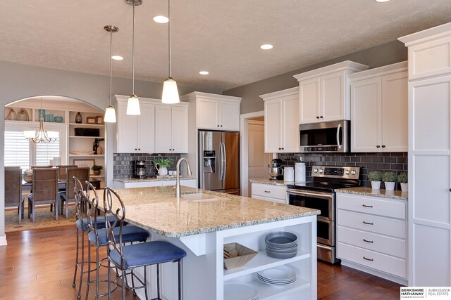 kitchen featuring dark wood finished floors, white cabinets, stainless steel appliances, open shelves, and a sink