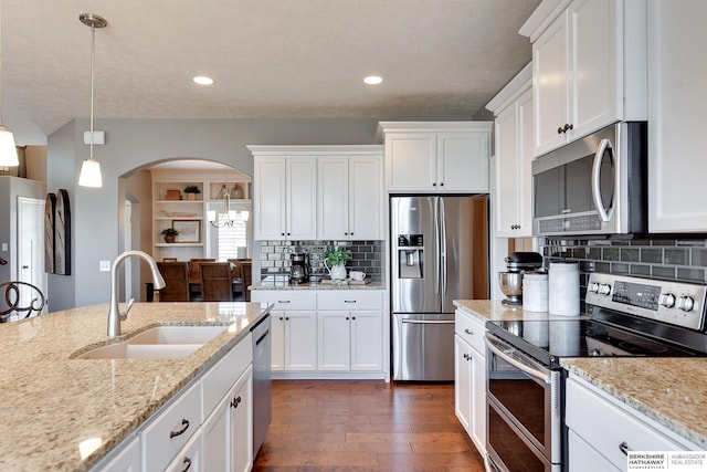 kitchen featuring arched walkways, stainless steel appliances, dark wood-type flooring, a sink, and white cabinets