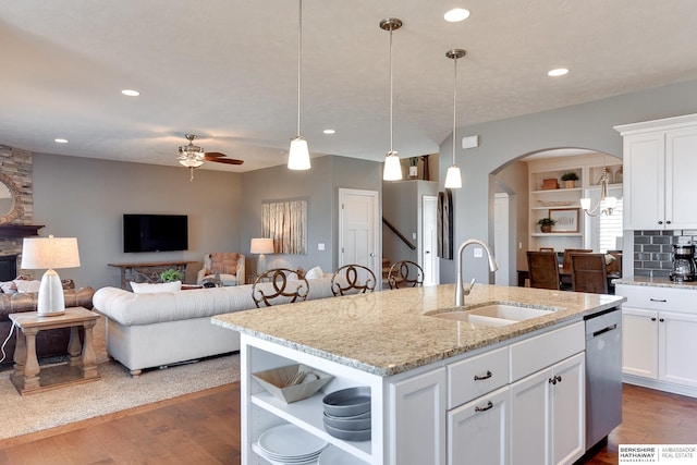 kitchen with stainless steel dishwasher, open floor plan, a sink, and wood finished floors