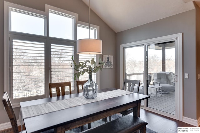 dining space featuring vaulted ceiling, wood finished floors, and baseboards