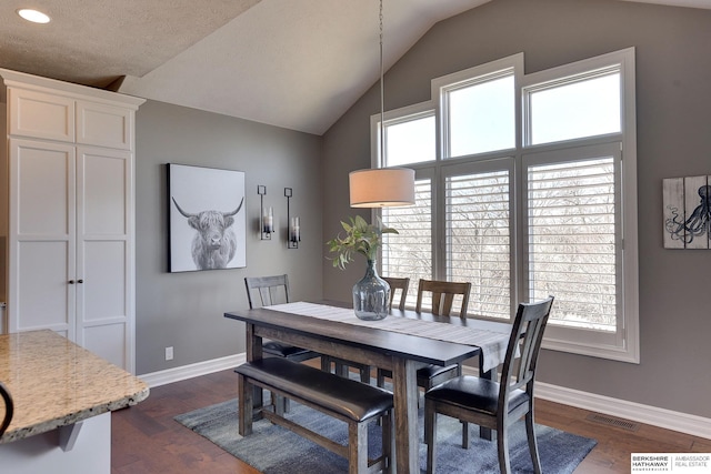 dining space featuring dark wood-style floors, vaulted ceiling, visible vents, and baseboards