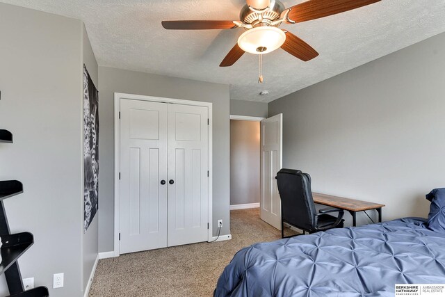 carpeted bedroom with a textured ceiling, ceiling fan, a closet, and baseboards