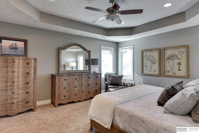 bedroom with a tray ceiling, visible vents, light carpet, a textured ceiling, and baseboards