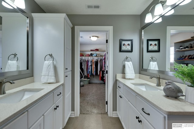 full bathroom featuring two vanities, tile patterned flooring, visible vents, and a sink