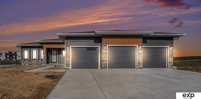 view of front of house featuring a garage, stone siding, and driveway