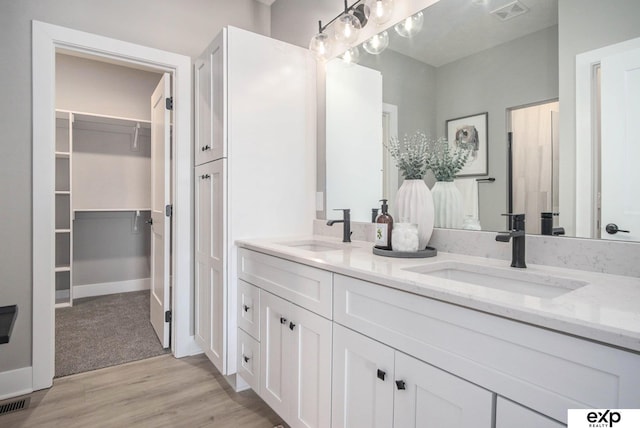 full bathroom featuring double vanity, wood finished floors, a sink, and visible vents