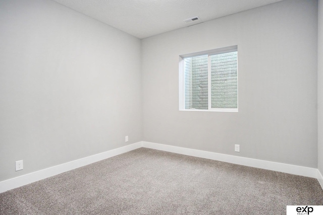 spare room featuring a textured ceiling, carpet flooring, visible vents, and baseboards