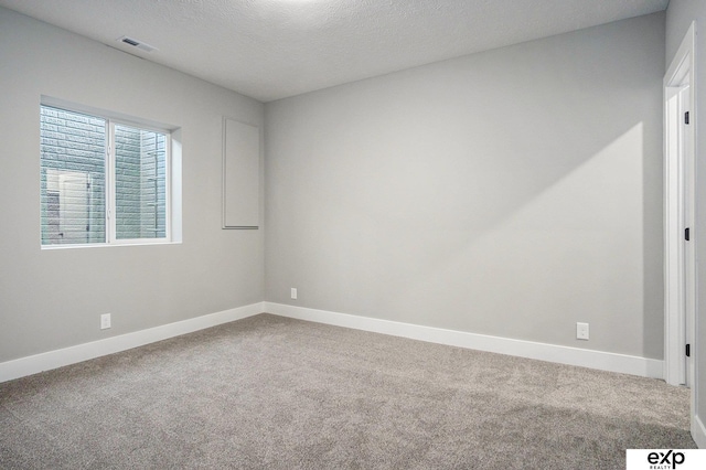 unfurnished room with carpet, visible vents, a textured ceiling, and baseboards