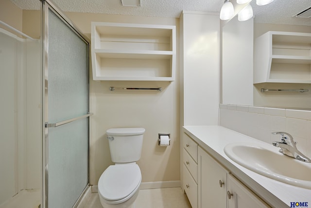 full bathroom featuring a shower stall, a textured ceiling, toilet, and vanity