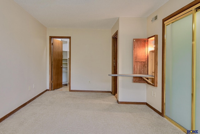 unfurnished bedroom with light colored carpet, visible vents, baseboards, a spacious closet, and a closet