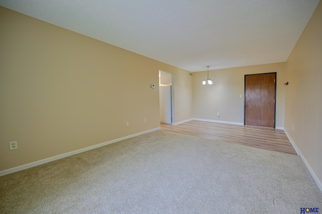 unfurnished room featuring light carpet, a textured ceiling, and baseboards