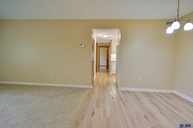 empty room featuring light wood-type flooring, visible vents, and baseboards