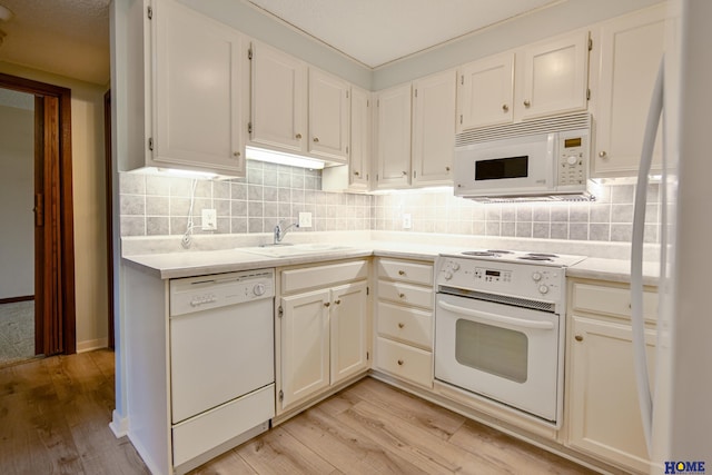 kitchen featuring light countertops, white appliances, a sink, and white cabinetry