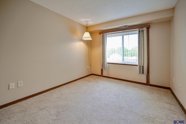 empty room with carpet, a textured ceiling, and baseboards