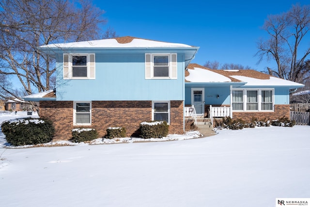 tri-level home featuring covered porch and brick siding