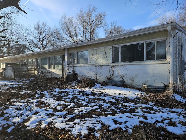 snow covered property with brick siding