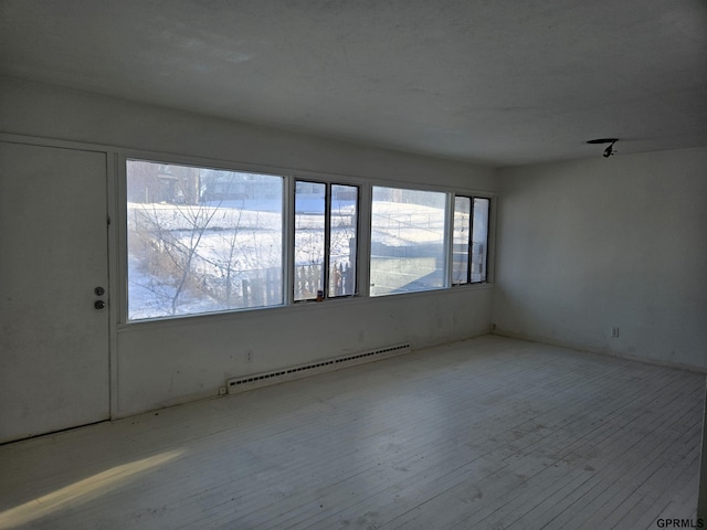 unfurnished room with light wood finished floors and a baseboard radiator