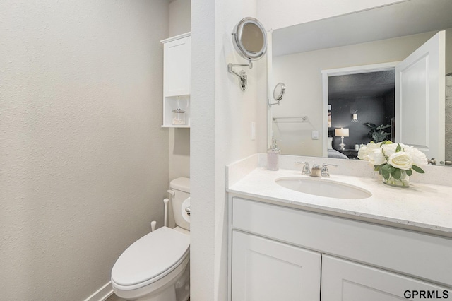 bathroom featuring toilet, a textured wall, ensuite bath, and vanity