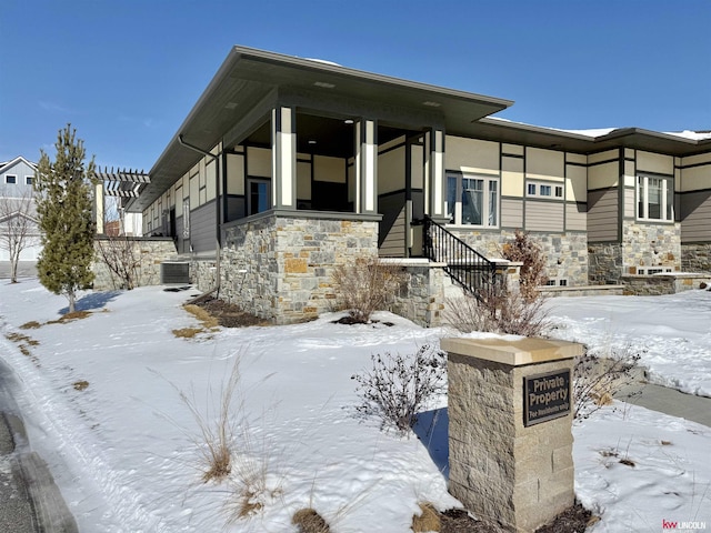 view of front of house with central air condition unit and stone siding