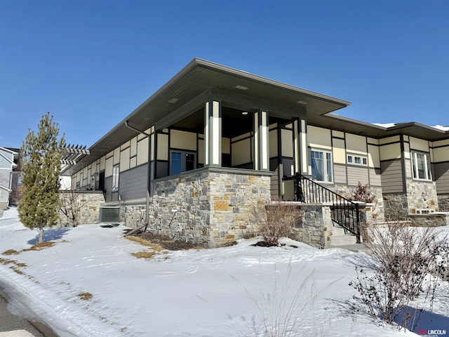 view of front of house with central AC unit and stone siding