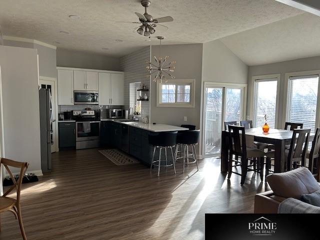 kitchen featuring stainless steel appliances, a breakfast bar, white cabinetry, light countertops, and pendant lighting