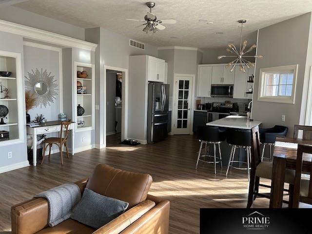 interior space with dark wood-type flooring, visible vents, baseboards, and ceiling fan with notable chandelier