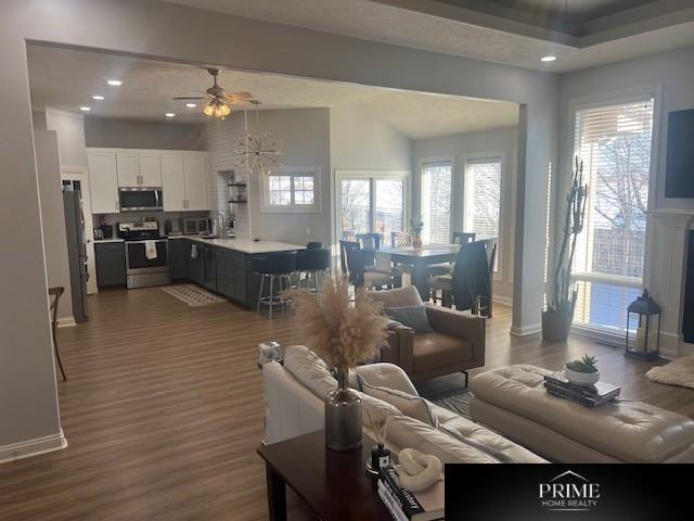 living area with dark wood-type flooring, recessed lighting, ceiling fan, and baseboards