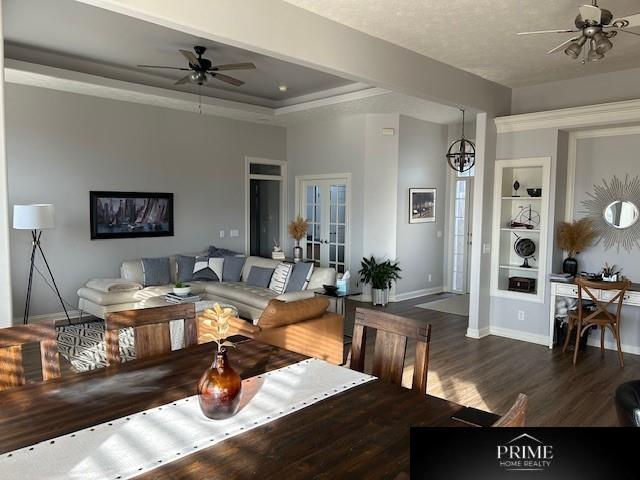 living room featuring dark wood-style flooring, a ceiling fan, baseboards, french doors, and a tray ceiling